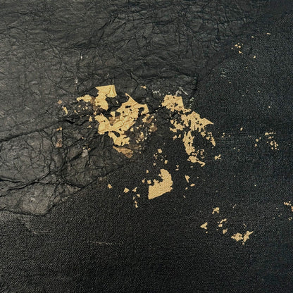 Black textured surface with gold leaf accents