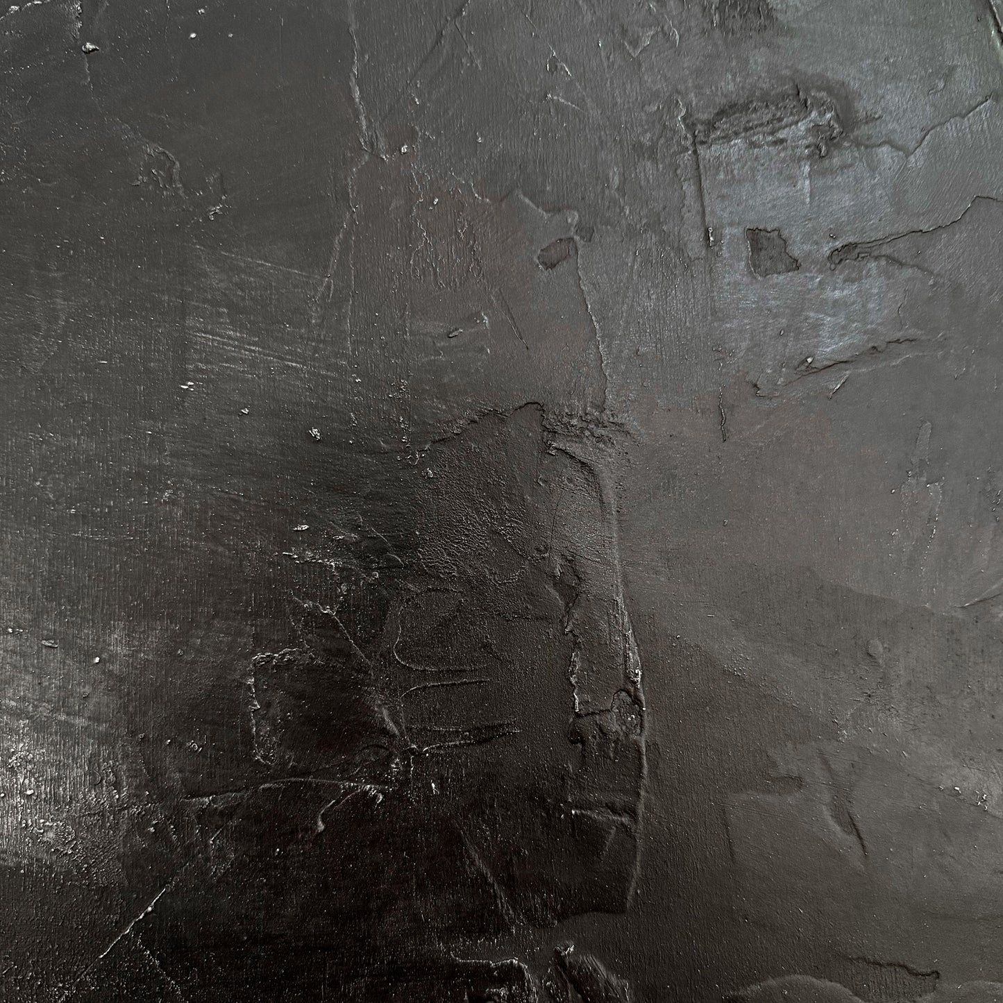 Close-up of a textured dark gray surface with visible cracks and imperfections.