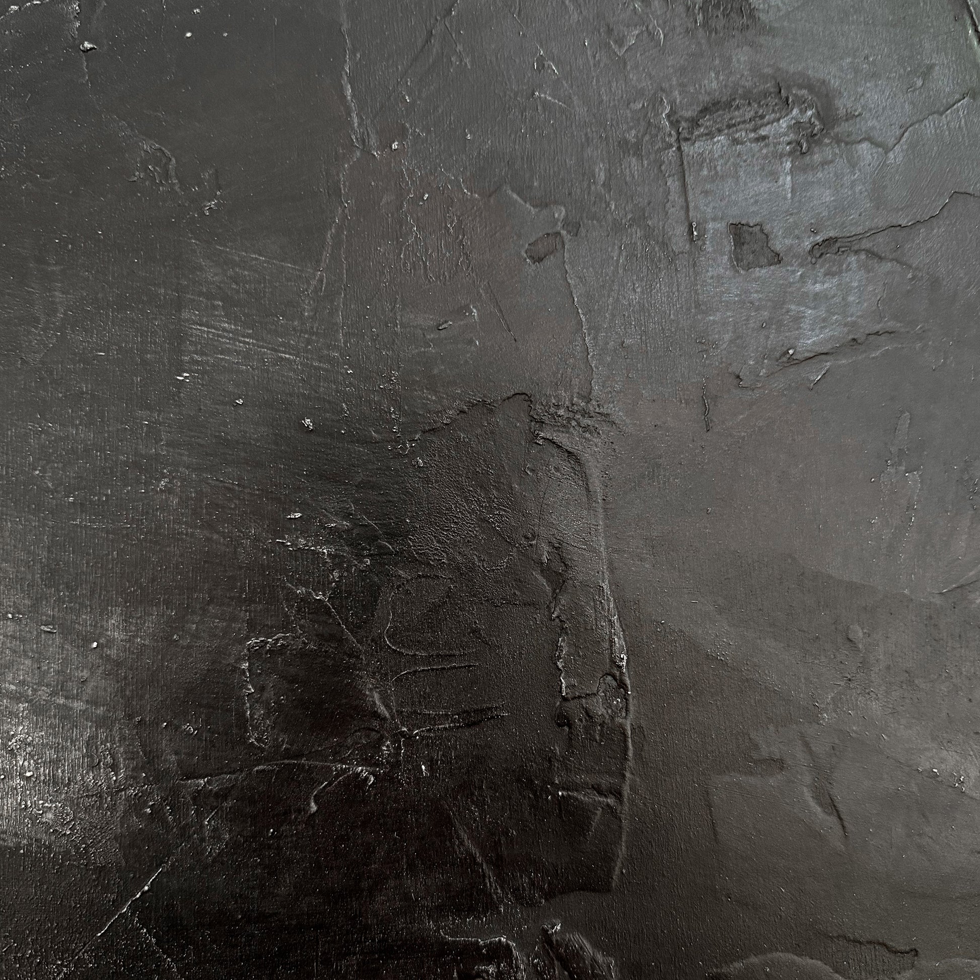 Close-up of a textured dark gray surface with visible cracks and imperfections.