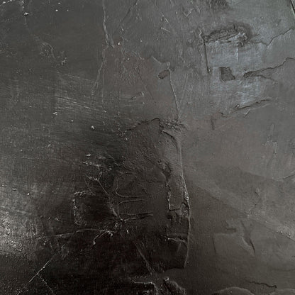 Close-up of a textured dark gray surface with visible cracks and imperfections.